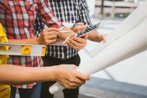 3 person analyzing construction plans on a tablet