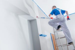 A contractor is painting a wall.